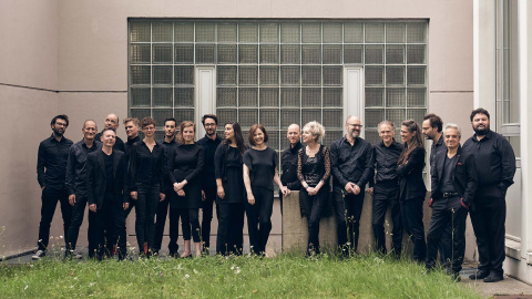 Das Ensemble Collegium Novum Zürich steht aufgereiht vor einer Scheibe eines Gebäudes