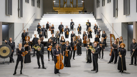 Mitglieder der Basel Sinfonietta stehen mit ihren Instrumenten vor einer Treppe