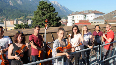 Junge Musiker*innen auf einer Brücke, im Hintergrund Berge